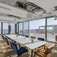 Salle de réunion moderne avec des tables, chaises et une vue sur la ville.
