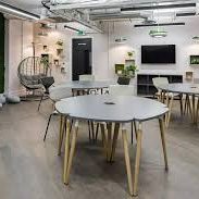 Salle de réunion moderne avec des tables rondes et des plantes décoratives.