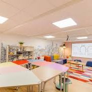 Salle de classe moderne avec des tables colorées et des murs décorés de dessins urbains.