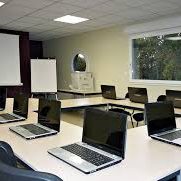 Salle de réunion avec des ordinateurs portables alignés sur des tables.