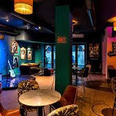 Intérieur d'un bar avec des lumières colorées, des sièges confortables et des œuvres d'art.